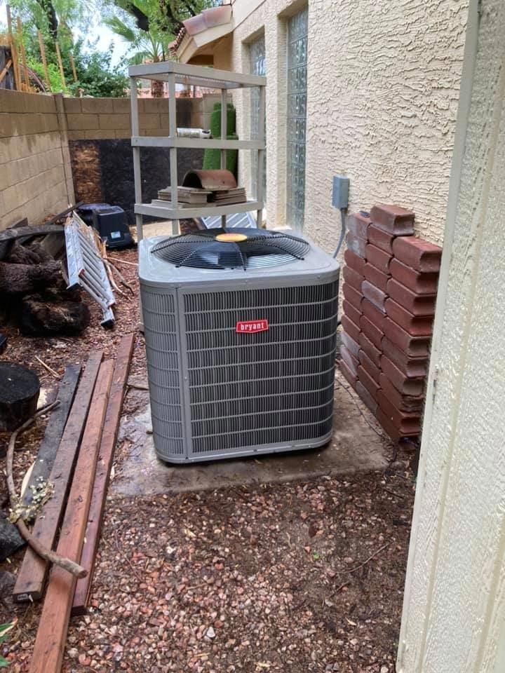 A large air conditioner is sitting in the backyard of a house.