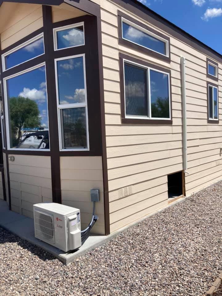 A mobile home with a lot of windows and a small air conditioner on the side of it.