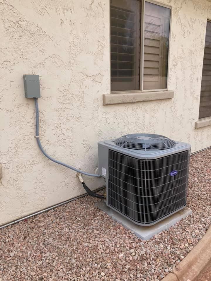 An air conditioner is sitting on the side of a building next to a window.