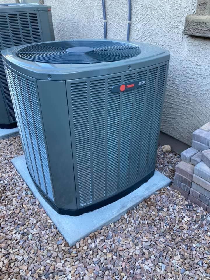 A large air conditioner is sitting on top of a pile of gravel.