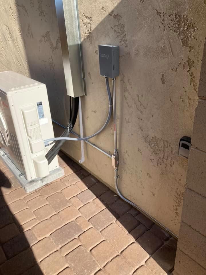 An air conditioner is sitting on a brick sidewalk next to a wall.