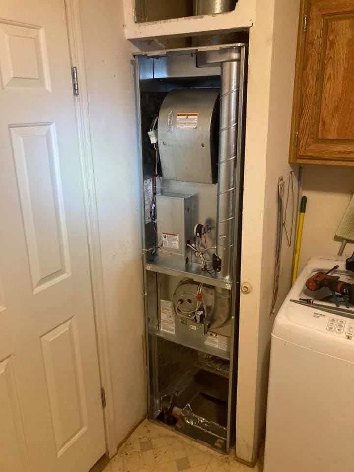 An air conditioner is sitting in a closet next to a washer and dryer.