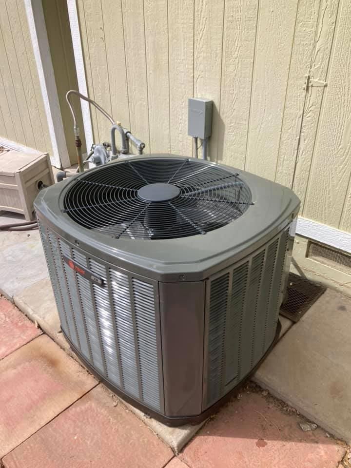 A large air conditioner is sitting on the side of a building.