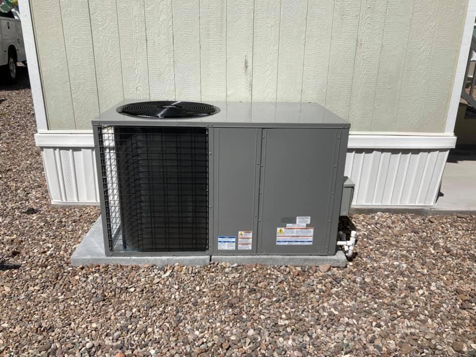 A large air conditioner is sitting outside of a mobile home.