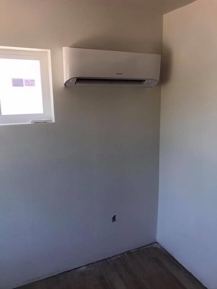 A room with a window and a wall mounted air conditioner.