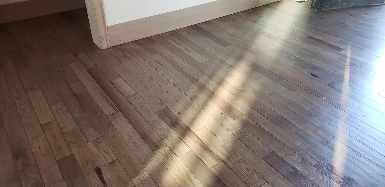 Wooden herringbone flooring with sunlight casting shadows.