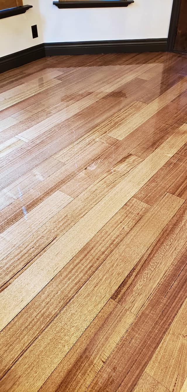 Wooden floor planks angled in a room with a window and dark trim.