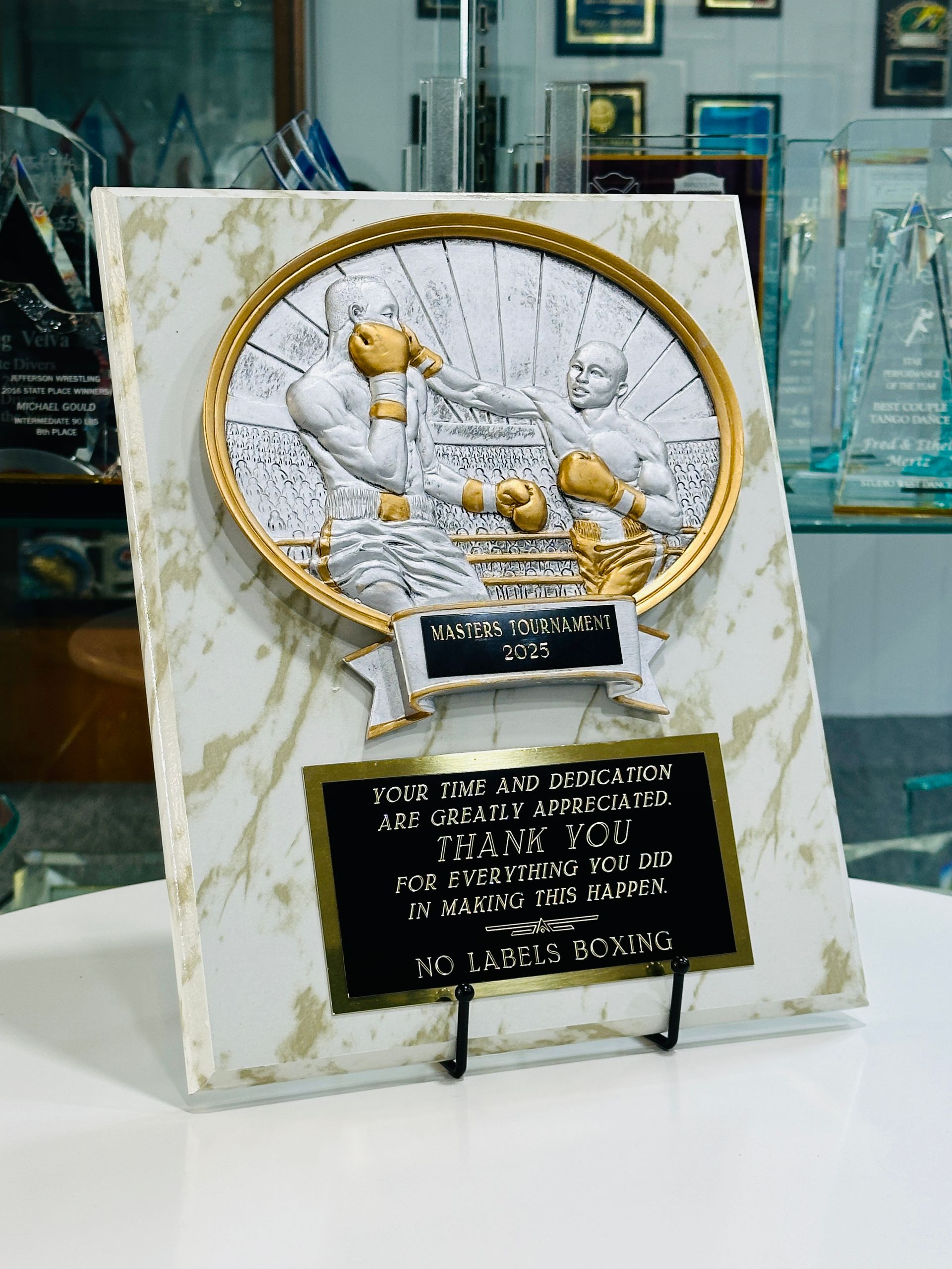 Boxing-themed award plaque: gold and white, two boxers in relief within a gold circle; black text on a marble-patterned base.
