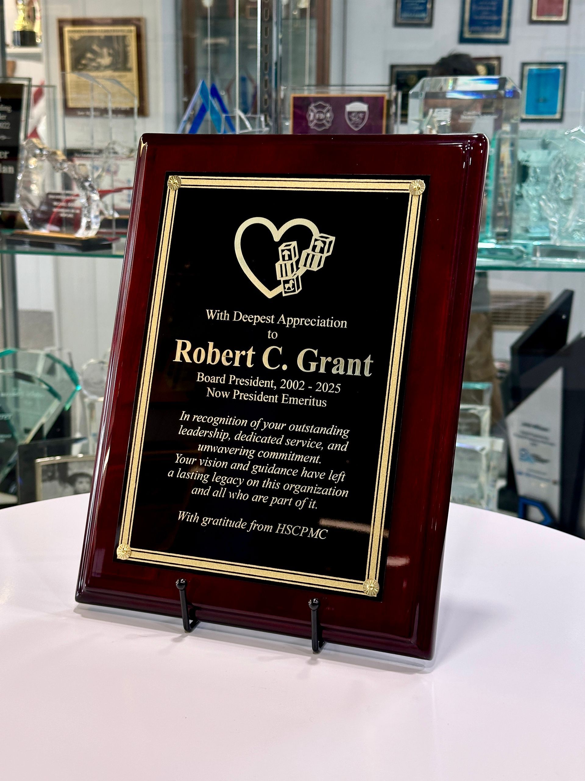 Plaque on a stand with gold trim and a black plate. The plaque is dedicated to Robert C. Grant.