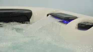 Smartphone and small remote submerged in bubbling water, with a blue light glowing nearby
