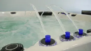Spa tub jets spraying water, with blue knobs on the control panel.