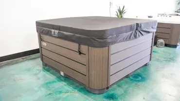 Gray hot tub with wood paneling in a bright room with a turquoise floor