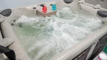 Bubble-filled hot tub with water jets and colorful drink cans on the center tray
