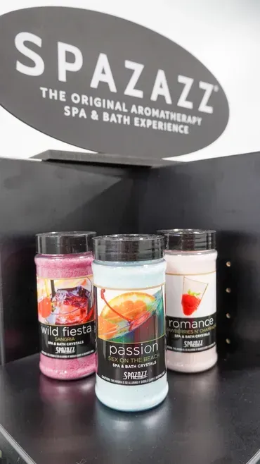 Spa display with three bath salts or candles on a shelf under a “SPAZAZZ” sign
