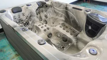 Empty beige hot tub with multiple jets and cup holders, viewed from above