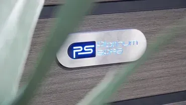 Close-up of a silver PS badge with blue logo on a brushed metal surface