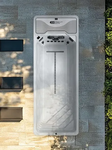 Wall-mounted white outdoor electrical charging unit on a stone wall, beside black light fixtures.
