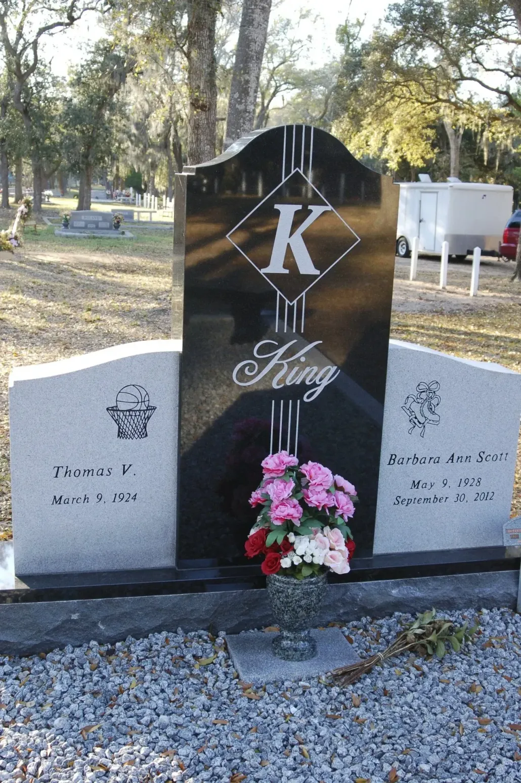 Headstone in cemetery; black central marker with 