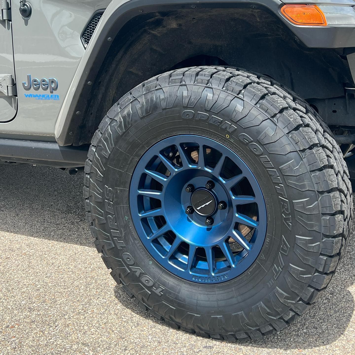 A jeep with blue wheels and tires is parked on the side of the road.