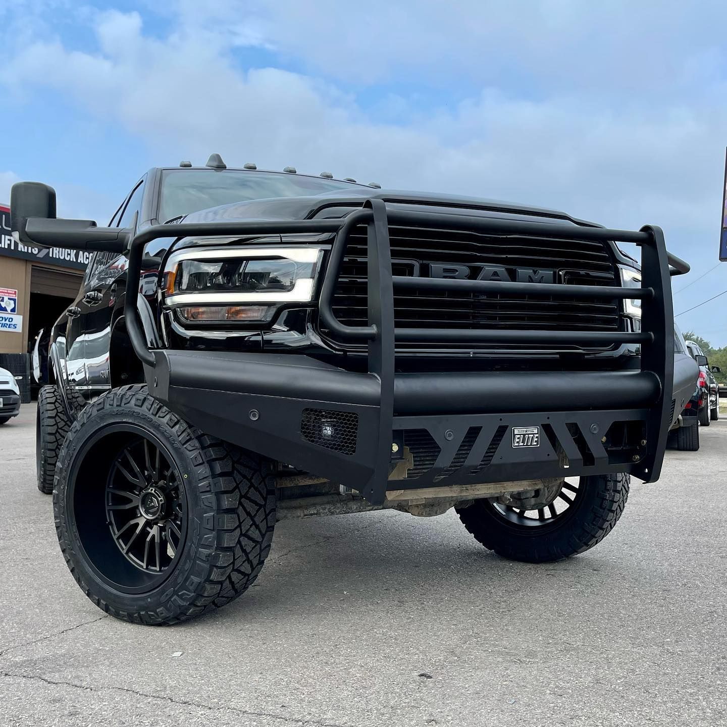 A black truck with a black bumper is parked in a parking lot.
