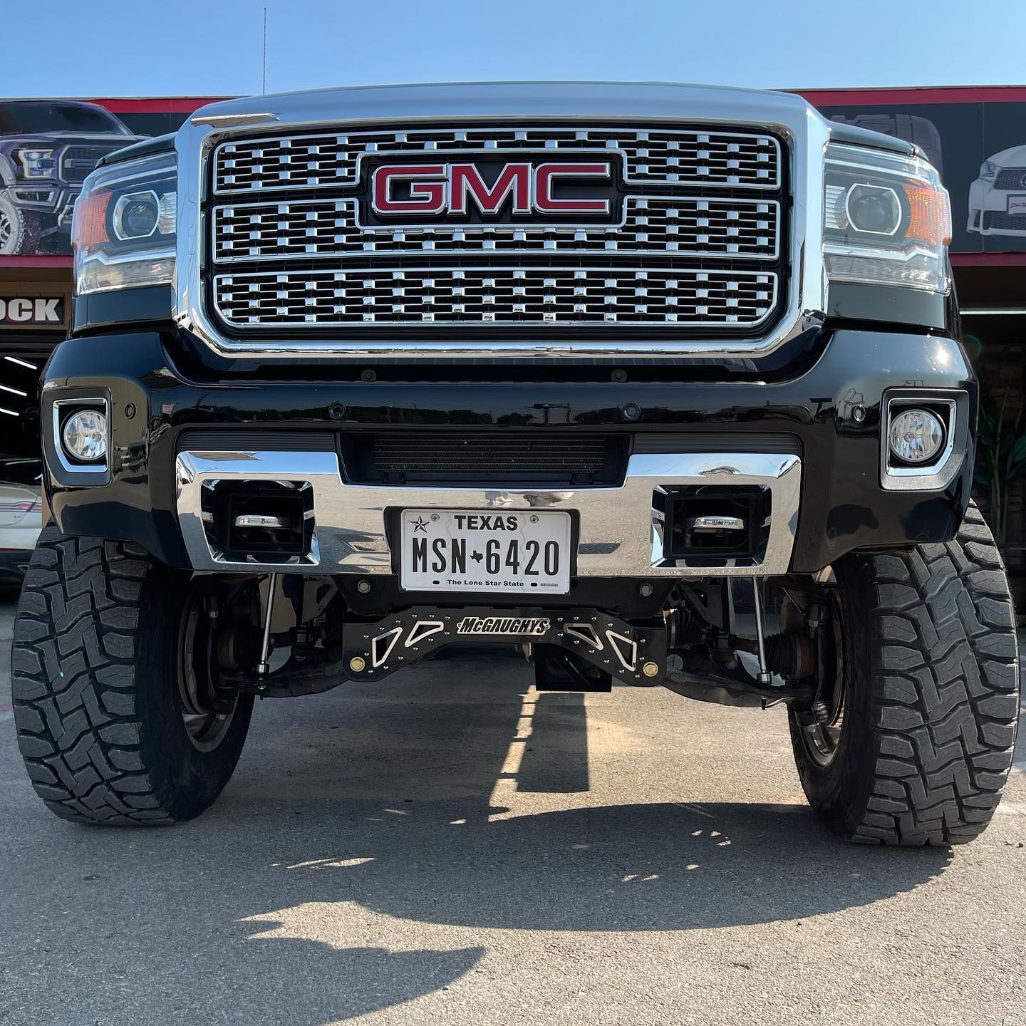 A gmc truck is parked in front of a car dealership