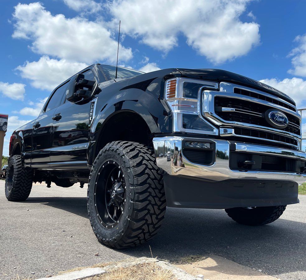A black ford truck is parked on the side of the road