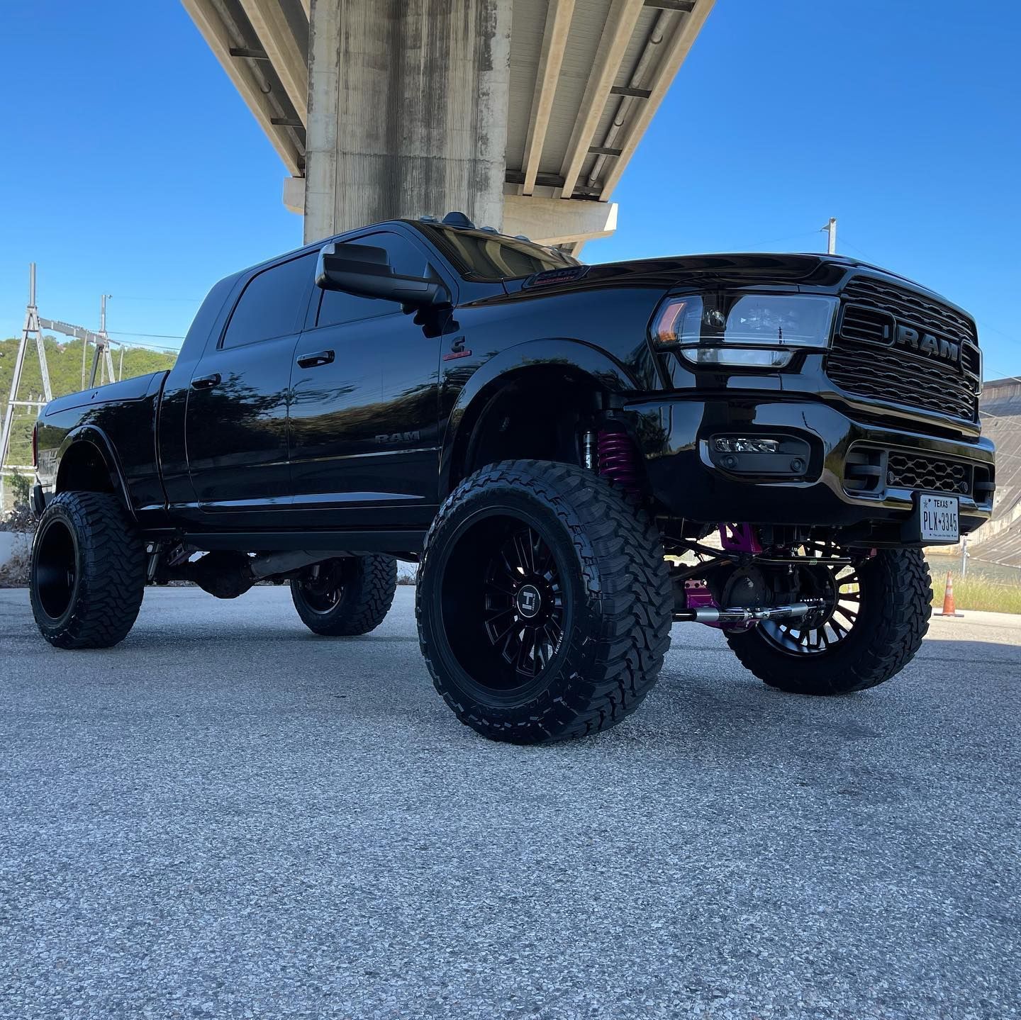 A black truck is parked under a bridge.
