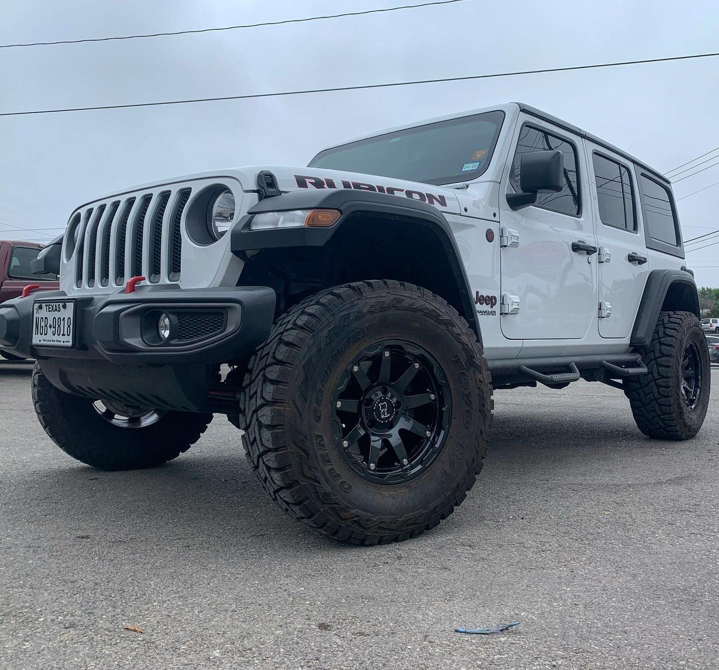 A white jeep wrangler is parked in a parking lot.