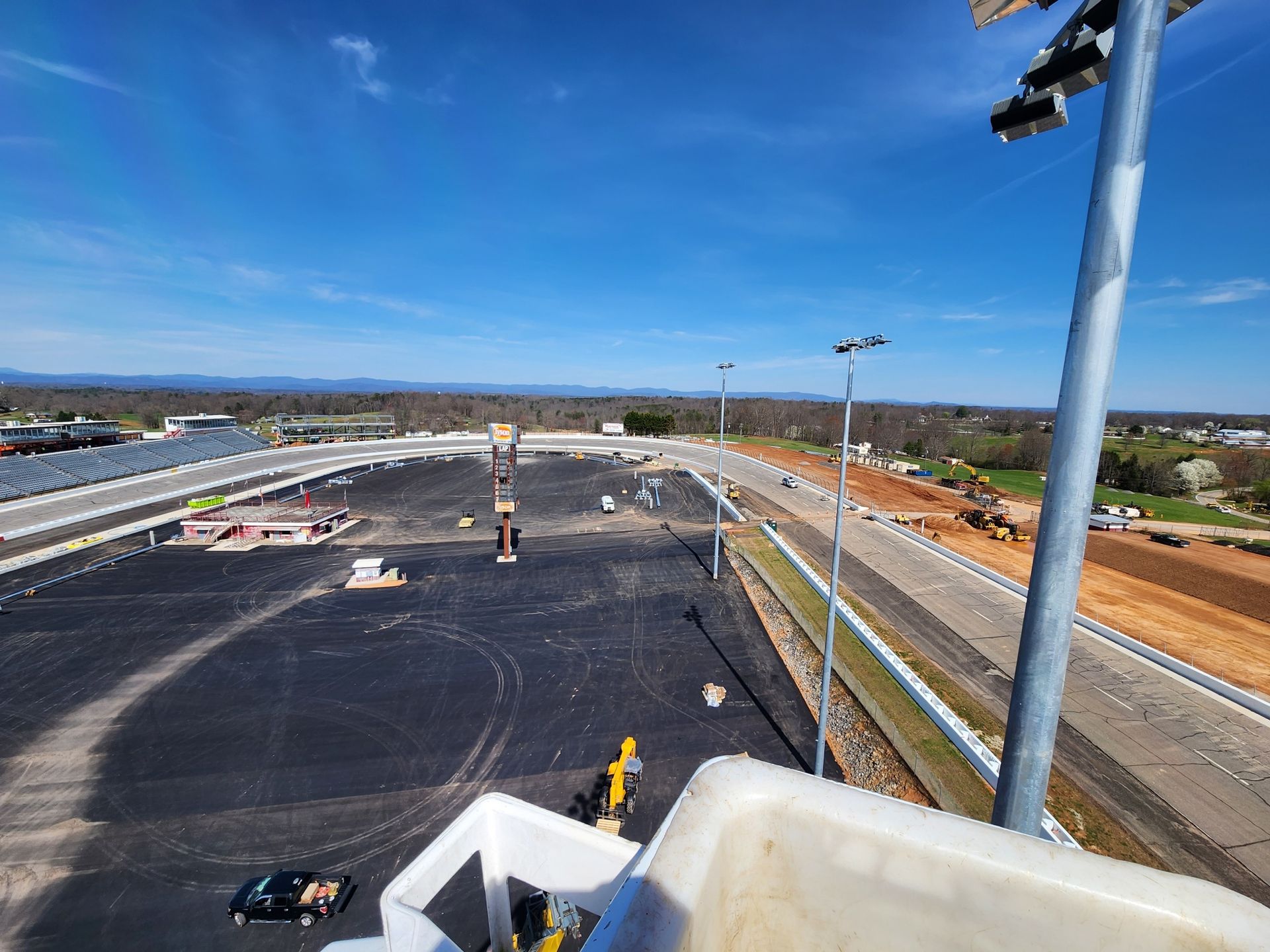 View of a racetrack under construction with clear blue sky and construction equipment.
