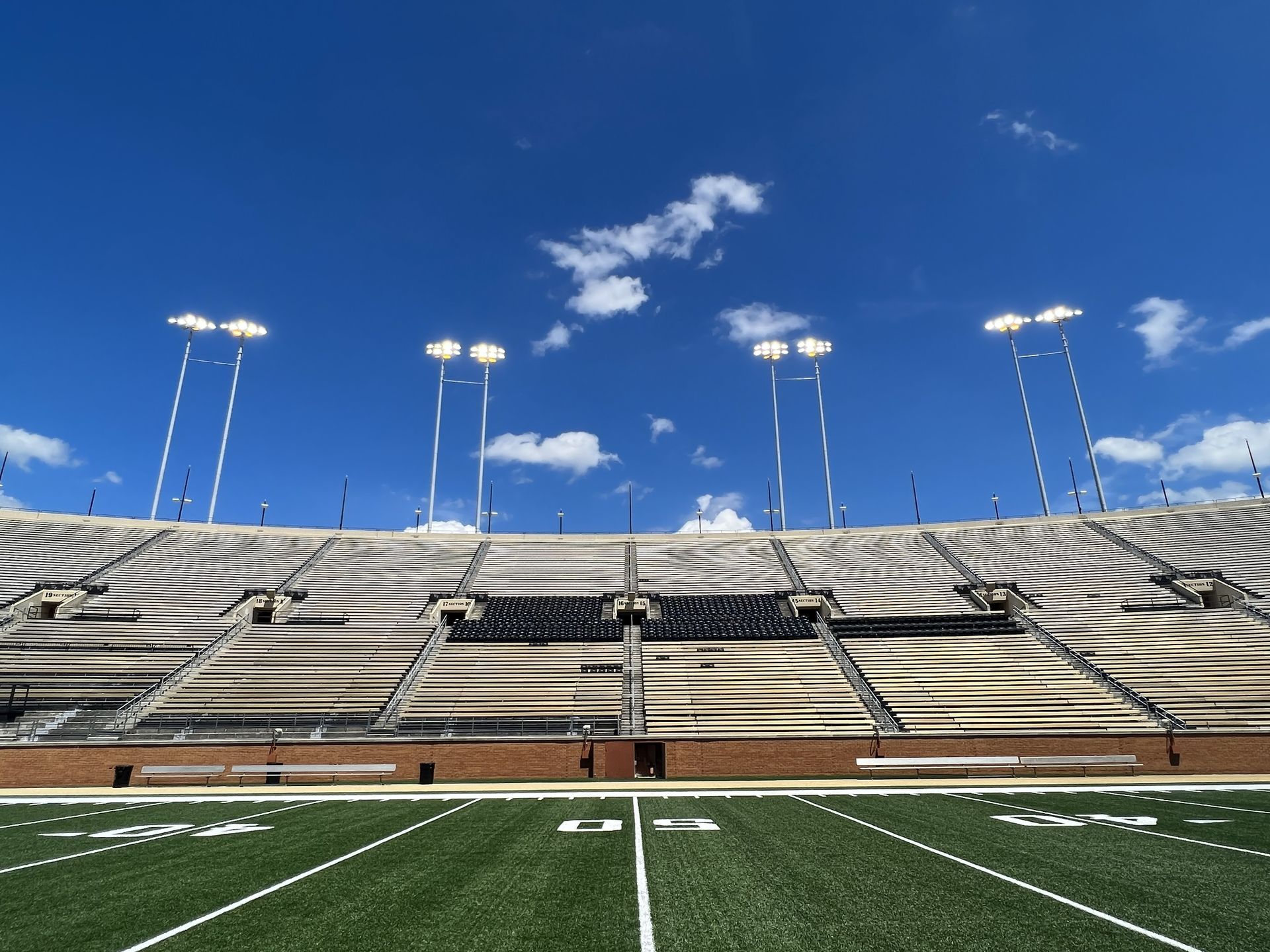 Electrical panel setup mounted on a wooden platform outdoors, with conduit pipes and surrounding trees.