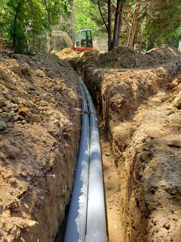 Stadium entrance with tall lights, track, brick buildings, and blue sky.
