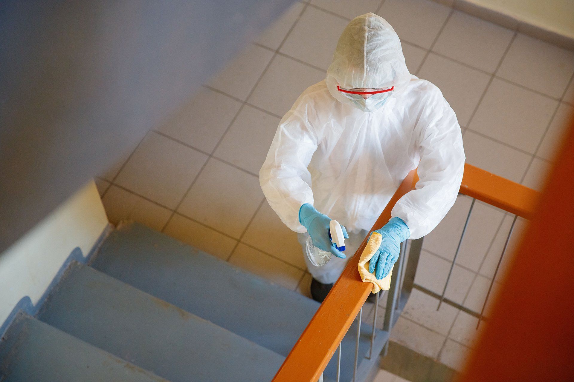 a man in a protective suit is cleaning the railing of a staircase 