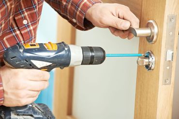 a man is using a drill to fix a door handle