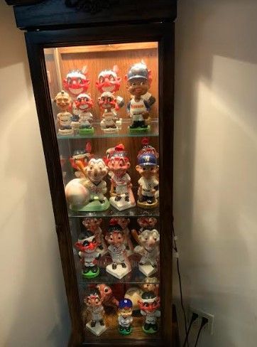 Baseball bobblehead figurines displayed in a glass-front cabinet.