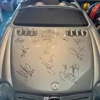 Silver car hood covered with autographs.