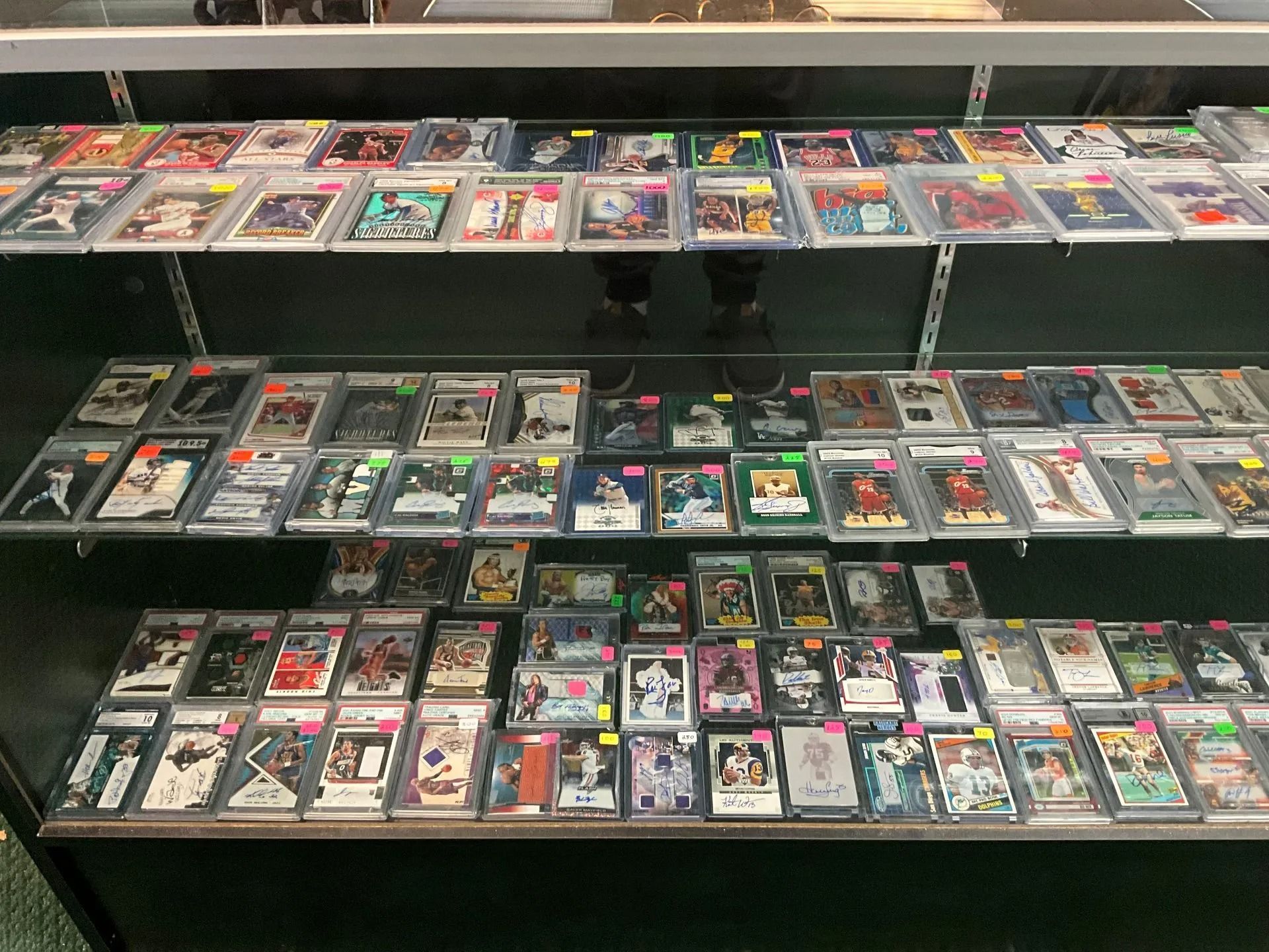 Sports trading cards displayed in a lit glass cabinet in a store.