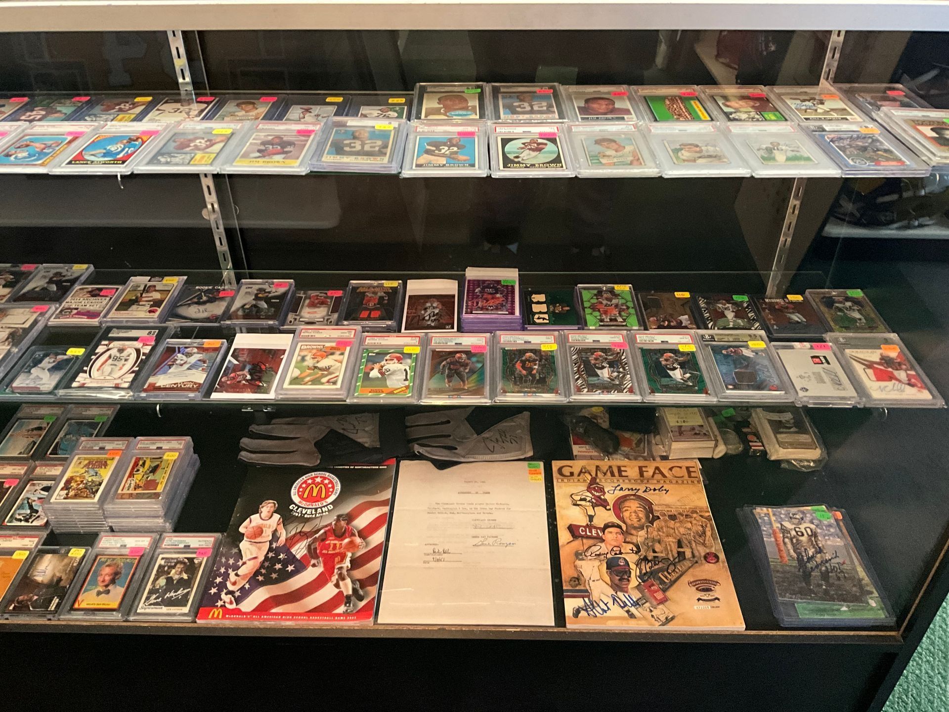 Display case with sports cards on shelves, including graded cards and memorabilia.