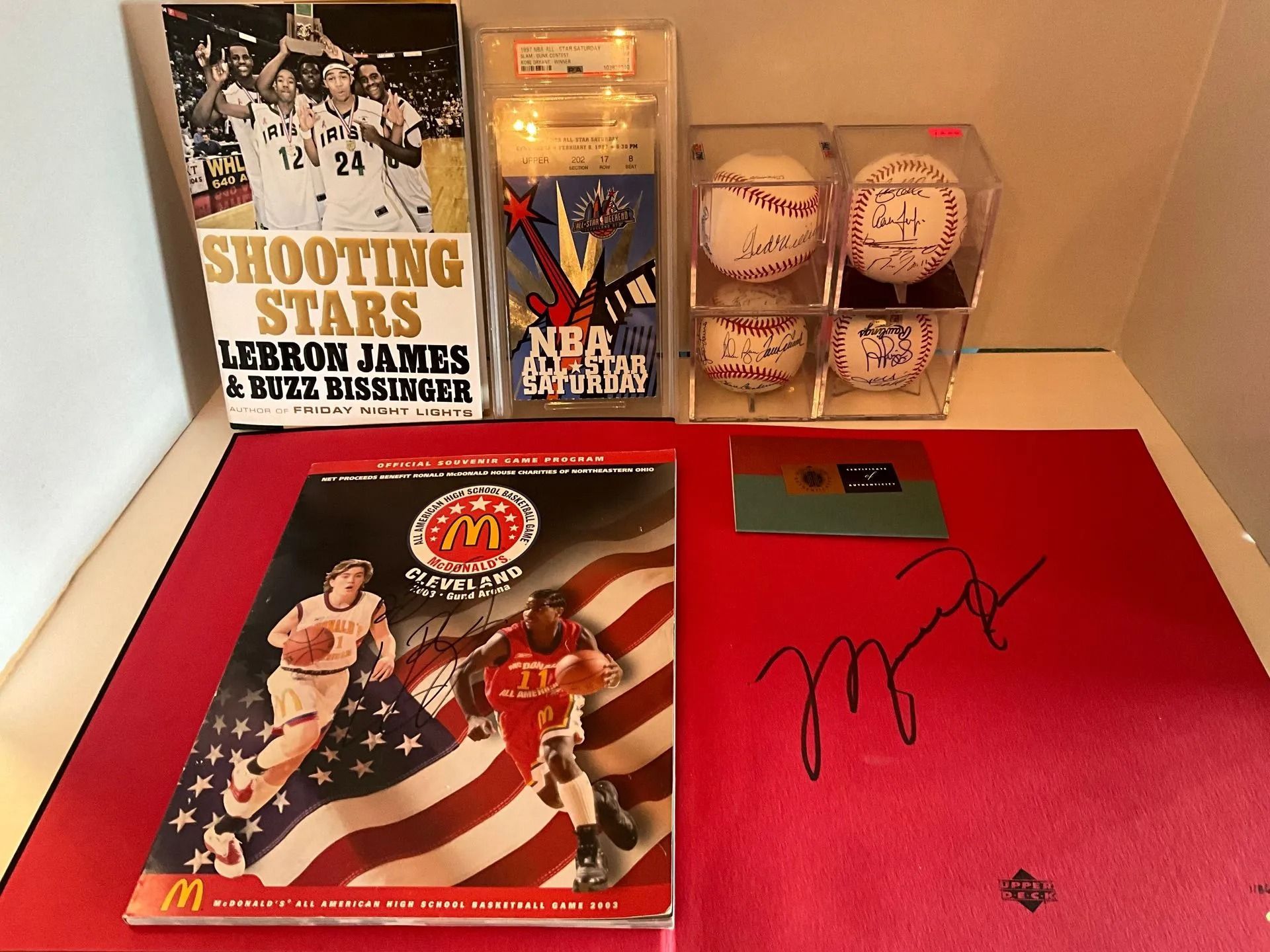 Basketball memorabilia: books, signed balls, McDonald's promotion, and signature on a red mat.