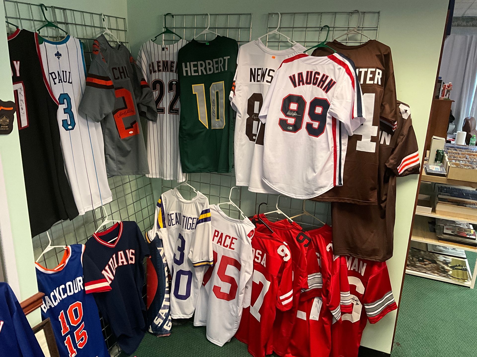 Jerseys hanging on a wall, various colors and styles, displayed in a store.