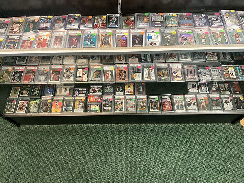 Rows of graded sports cards on display shelves in a store.