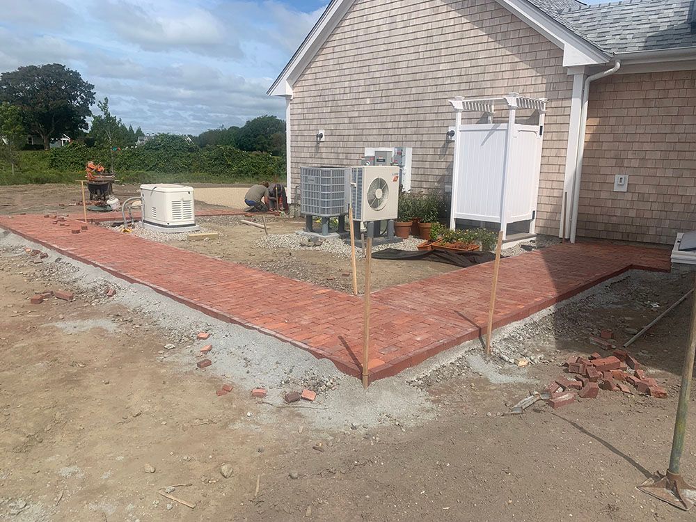 A brick patio being constructed in front of a house, adding a charming outdoor space.