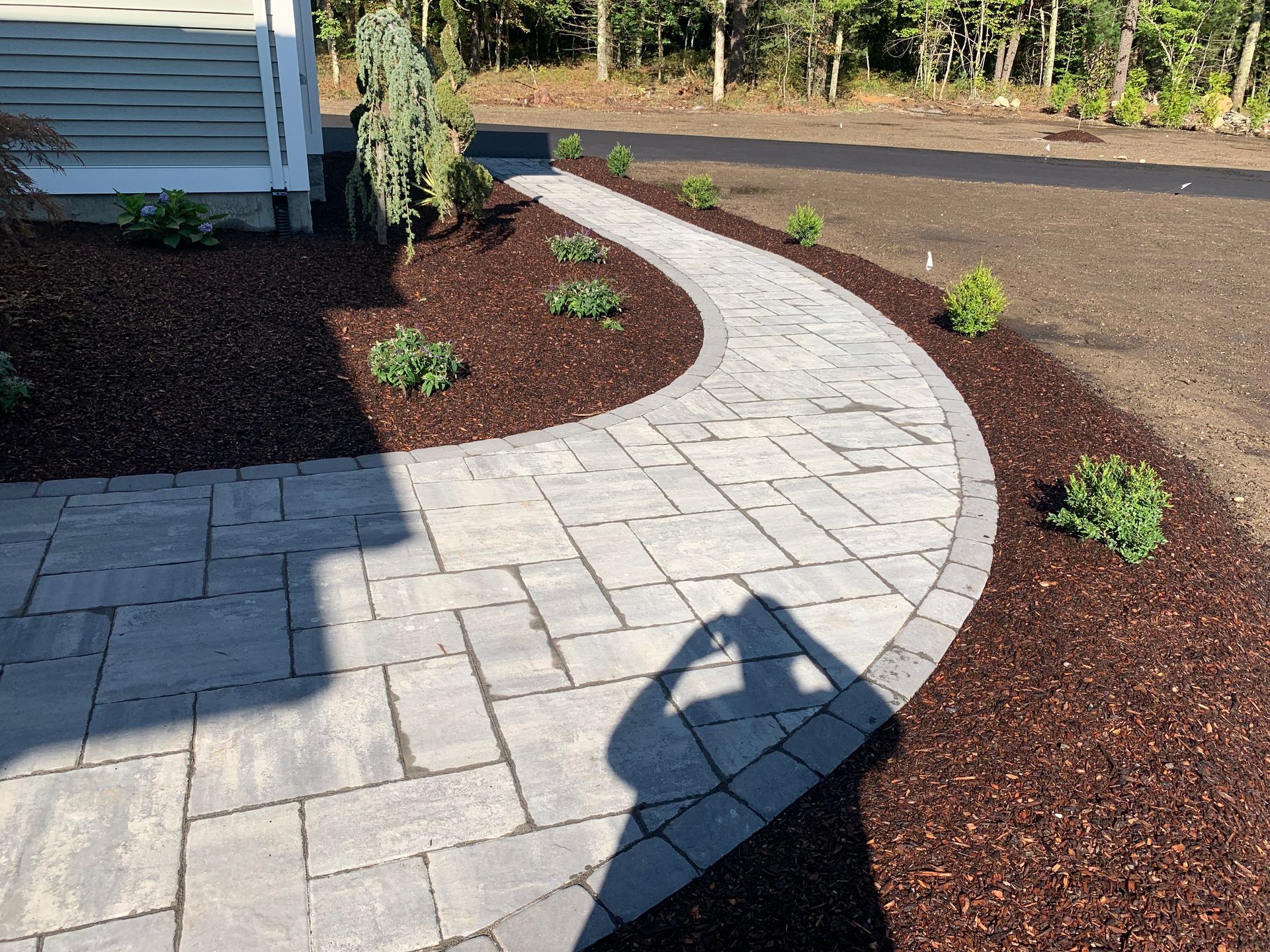 A person standing in front of a walkway, casting a shadow.