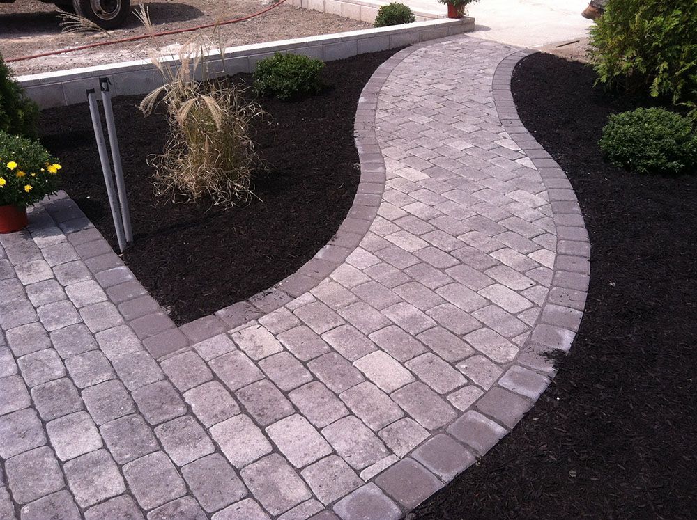 A walkway with a brick path winding through beautifully landscaped surroundings.