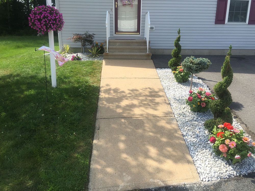 A colorful flower bed with rocks in front of a house.