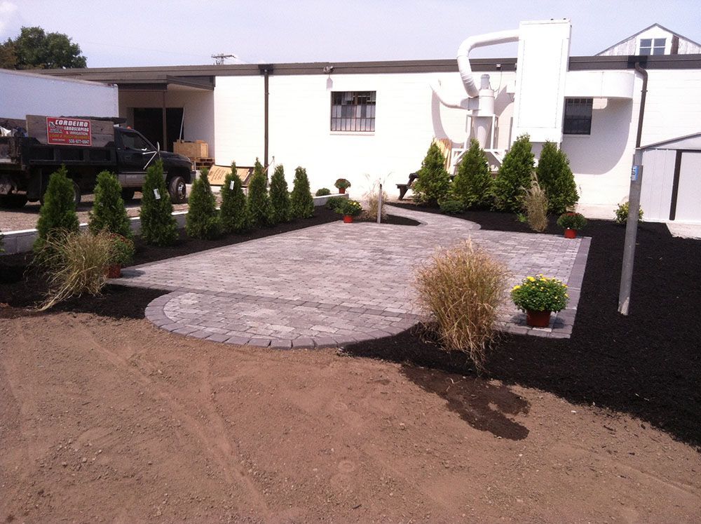 A brick pathway winds through a beautifully landscaped patio.
