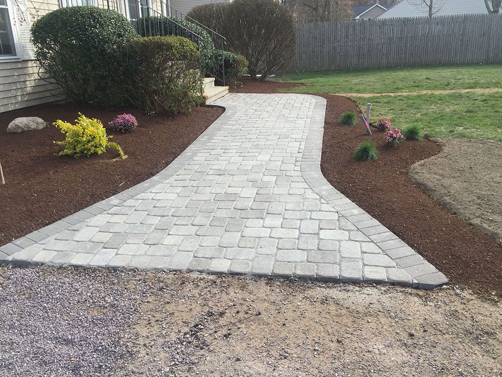A brick walkway winding through lush landscaping.