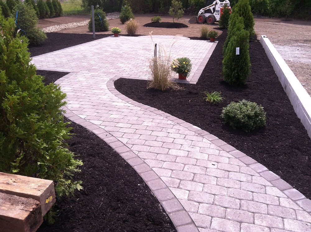 A scenic walkway with a brick path winding through beautifully landscaped surroundings.