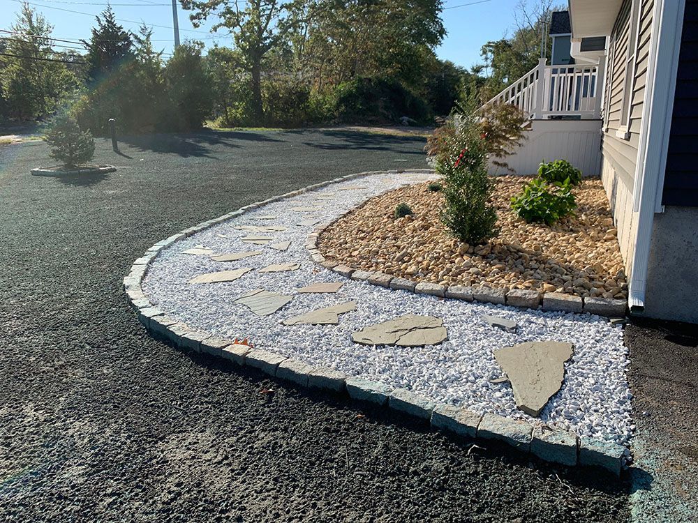 Scenic view of gravel driveway, rock wall, and trees.
