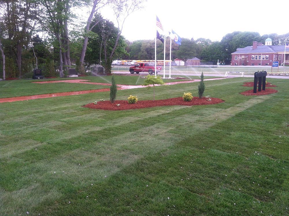 A water fountain and  a grassy landscape.