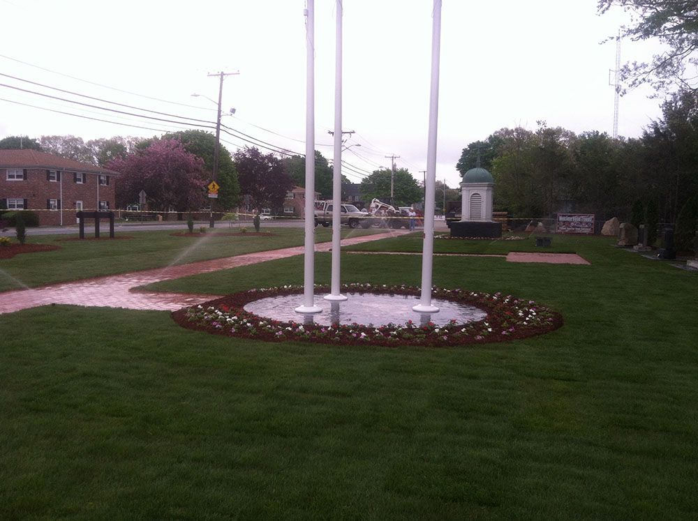 A serene park with a central fountain surrounded by lush green grass.